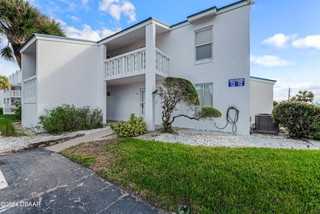 view of property exterior with a balcony, cooling unit, and a lawn