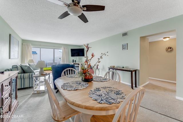 carpeted dining room with a textured ceiling and ceiling fan