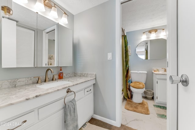 bathroom with vanity, toilet, and a textured ceiling