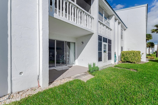 back of house with a lawn and a balcony