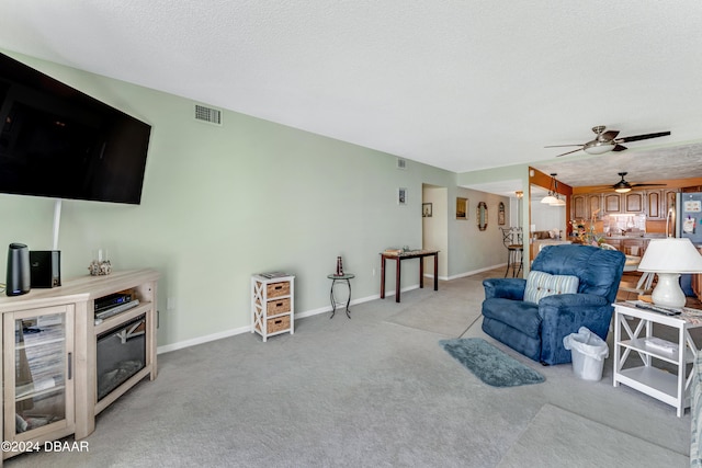 living room featuring light carpet, a textured ceiling, and ceiling fan