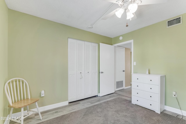 unfurnished bedroom featuring a textured ceiling, ceiling fan, light carpet, and a closet