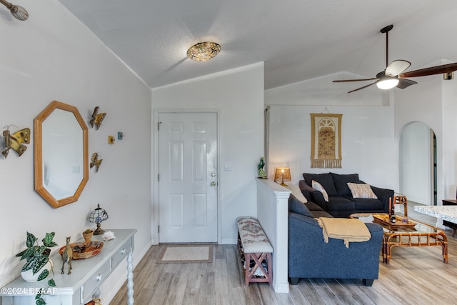 living room with ceiling fan, vaulted ceiling, and light hardwood / wood-style floors