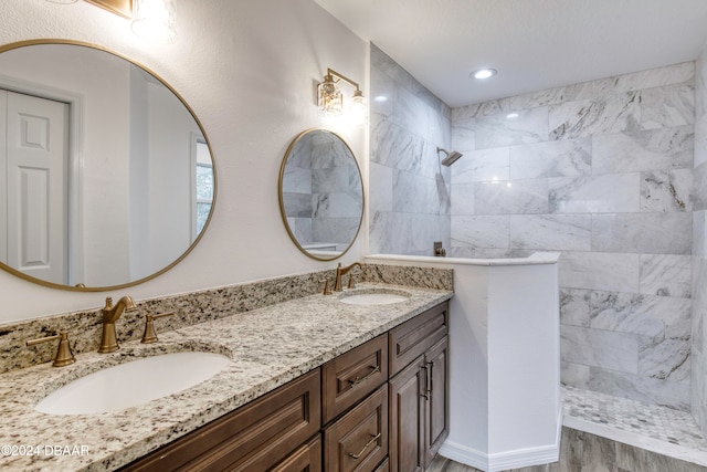 bathroom with wood-type flooring, a tile shower, and vanity