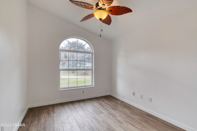 spare room with ceiling fan, light wood-type flooring, and vaulted ceiling