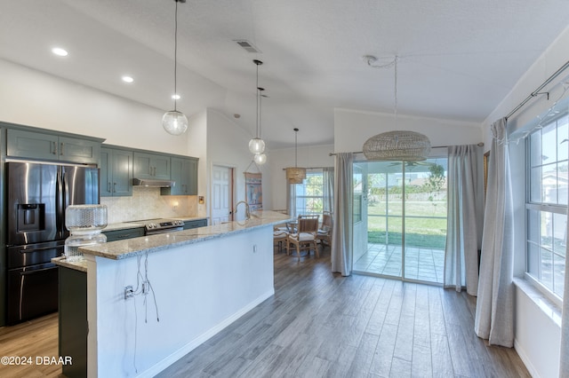 kitchen featuring light stone countertops, lofted ceiling, a kitchen island with sink, and stainless steel appliances