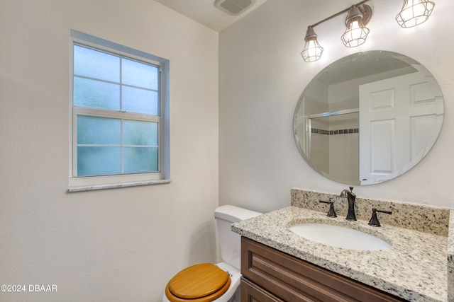 bathroom with walk in shower, vanity, and toilet