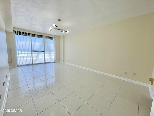 tiled empty room featuring a textured ceiling and a chandelier