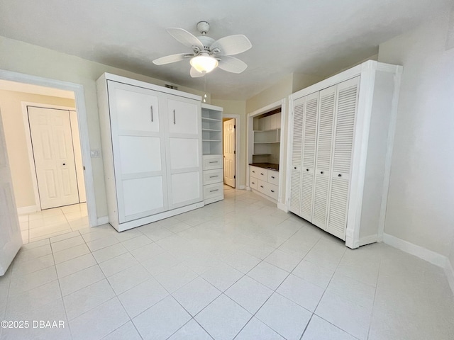 unfurnished bedroom featuring ceiling fan, two closets, and light tile patterned floors