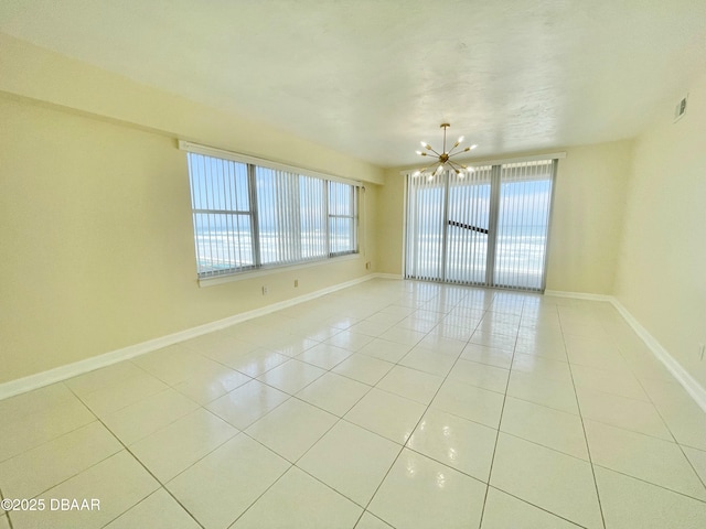 tiled empty room featuring an inviting chandelier