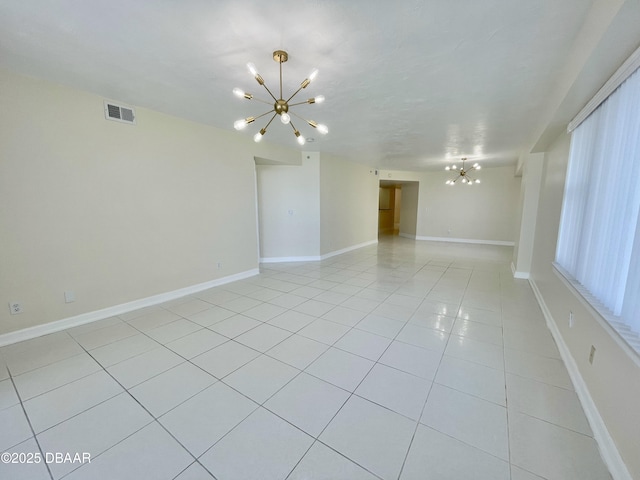 spare room featuring light tile patterned floors and an inviting chandelier