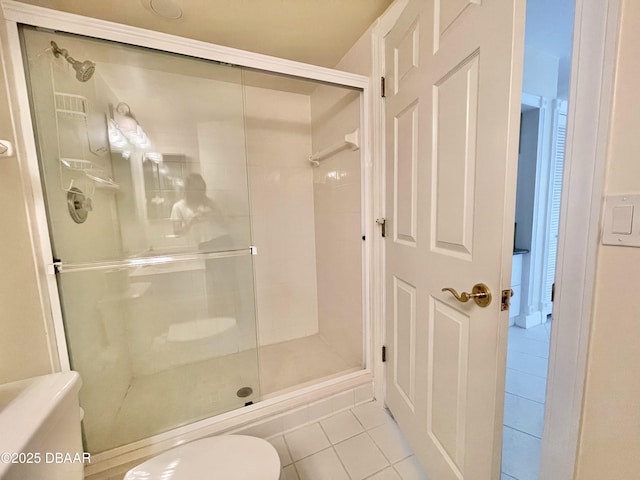 bathroom with toilet, a shower with shower door, and tile patterned flooring