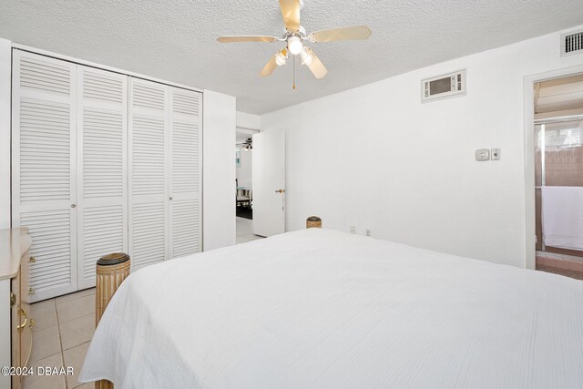 bedroom with light tile patterned floors, ceiling fan, a textured ceiling, and a closet