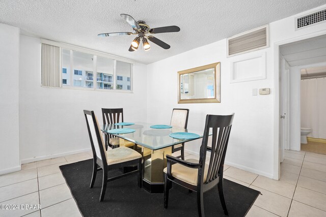 dining space with a textured ceiling, light tile patterned floors, and ceiling fan