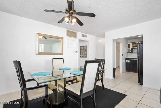 tiled dining space with a textured ceiling and ceiling fan