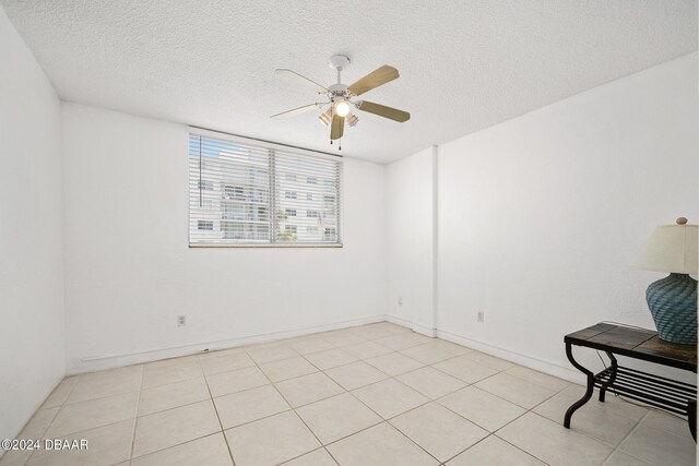 tiled empty room featuring a textured ceiling and ceiling fan