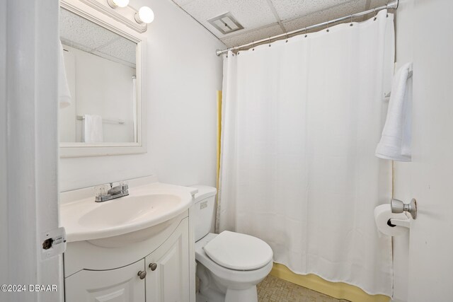 bathroom featuring toilet, a paneled ceiling, vanity, and curtained shower