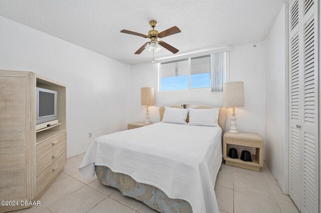 tiled bedroom featuring ceiling fan, a textured ceiling, and a closet