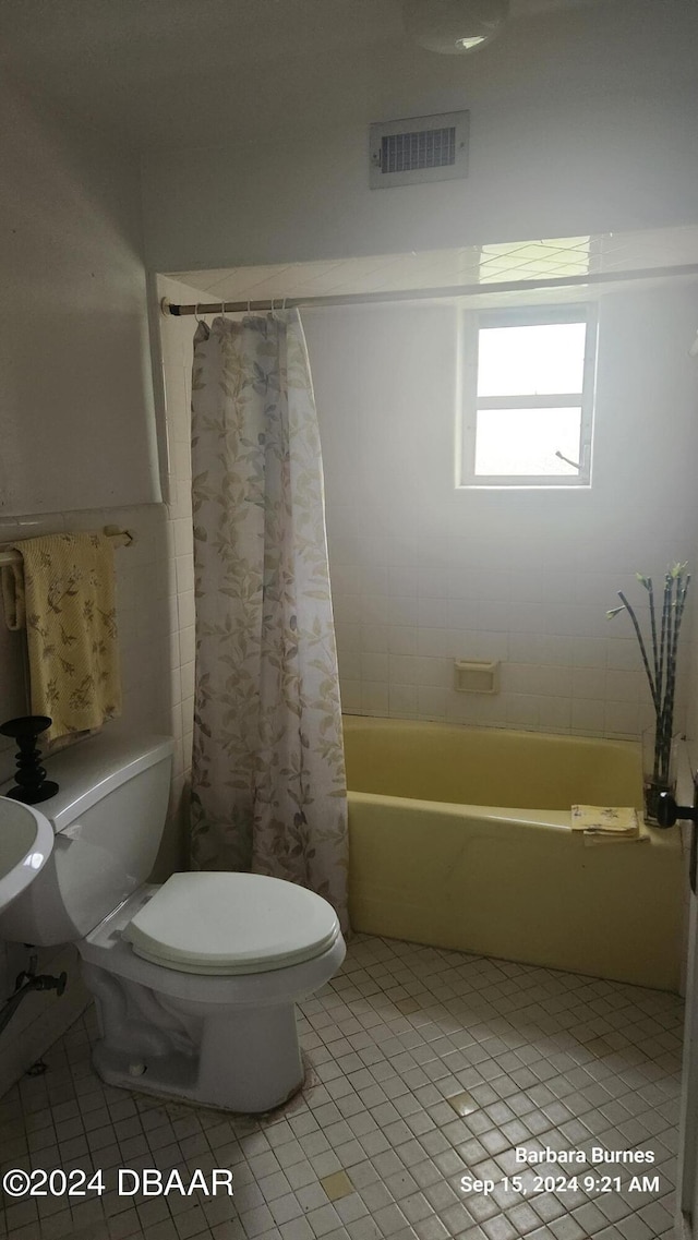 bathroom with tile patterned floors, shower / bath combo with shower curtain, and toilet