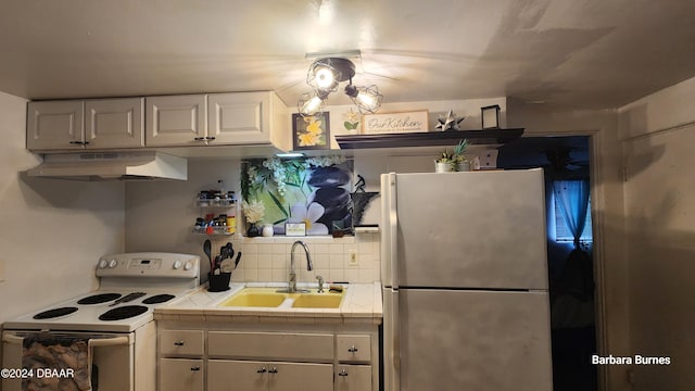 kitchen with tile countertops, white cabinets, sink, white electric stove, and stainless steel fridge