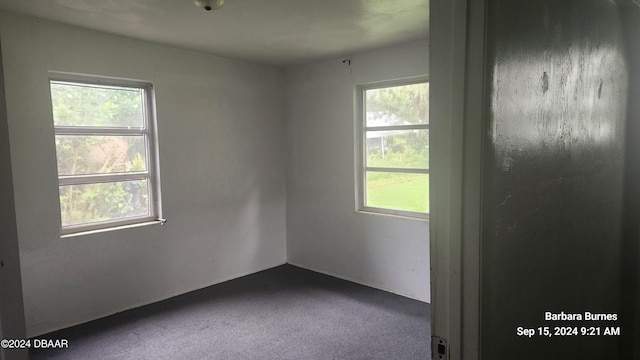 empty room featuring dark colored carpet and plenty of natural light