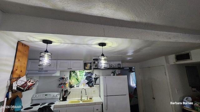 kitchen featuring white appliances, white cabinets, sink, hanging light fixtures, and tile counters