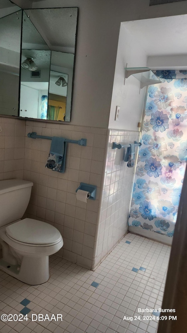 bathroom with tile patterned floors, toilet, and tile walls