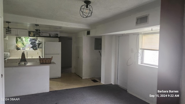 kitchen with white cabinets, a textured ceiling, white refrigerator, and pendant lighting