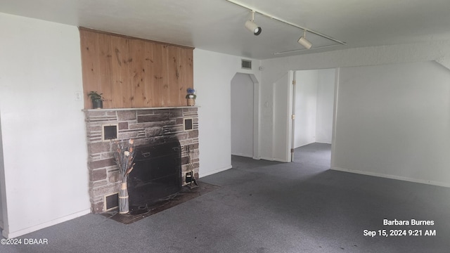 unfurnished living room featuring a fireplace, track lighting, and dark carpet