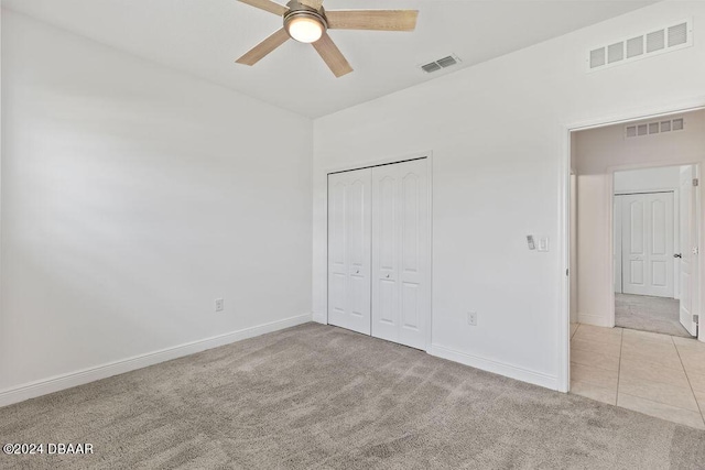 unfurnished bedroom with ceiling fan, light colored carpet, and a closet