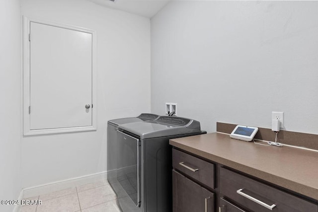 clothes washing area featuring cabinets, light tile patterned floors, and washer and dryer