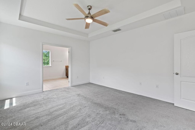 carpeted empty room with a tray ceiling and ceiling fan