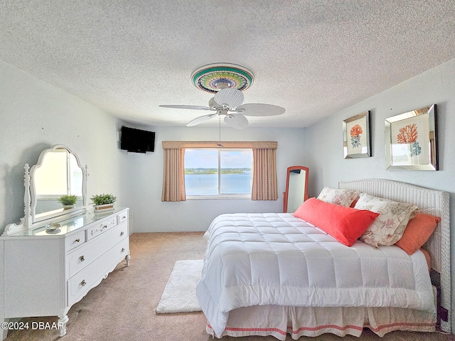 bedroom with ceiling fan, a textured ceiling, and light carpet