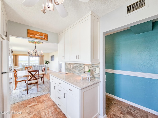 kitchen with tasteful backsplash, light stone counters, white fridge, and white cabinets