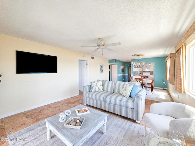 living room with ceiling fan with notable chandelier and a textured ceiling