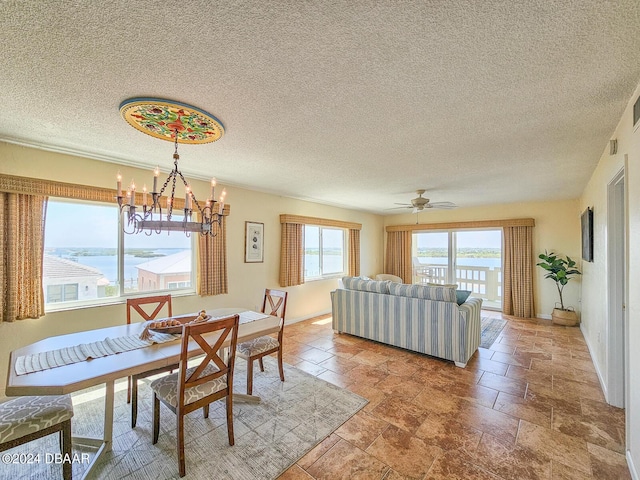 3606 S Peninsula Dr Unit 614, Port Orange, FL 32127 - dining area featuring a chandelier, a textured ceiling, a water view, a ceiling fan, and baseboards
