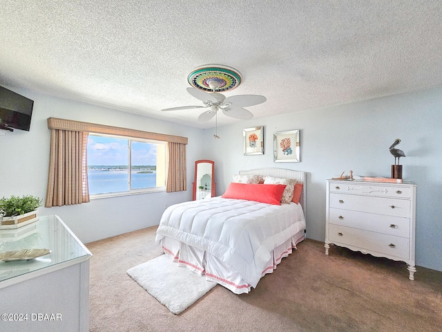 bedroom with carpet floors, a textured ceiling, a water view, and ceiling fan