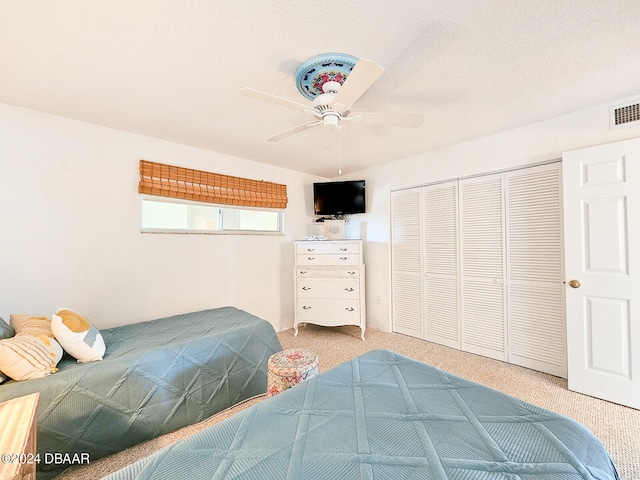 carpeted bedroom featuring a closet, a textured ceiling, and ceiling fan