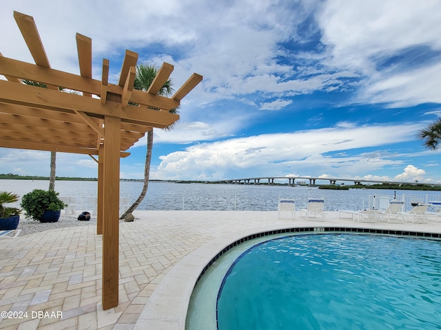 view of pool with a patio, a water view, and a pergola