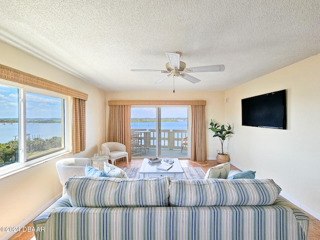 living room with a water view, a textured ceiling, and ceiling fan