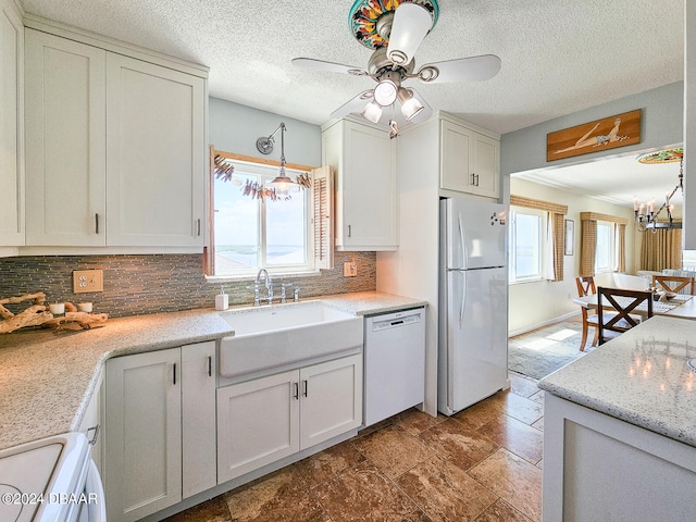 kitchen with sink, ceiling fan with notable chandelier, white appliances, white cabinets, and decorative backsplash