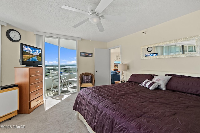 bedroom featuring expansive windows, carpet flooring, a textured ceiling, and access to outside