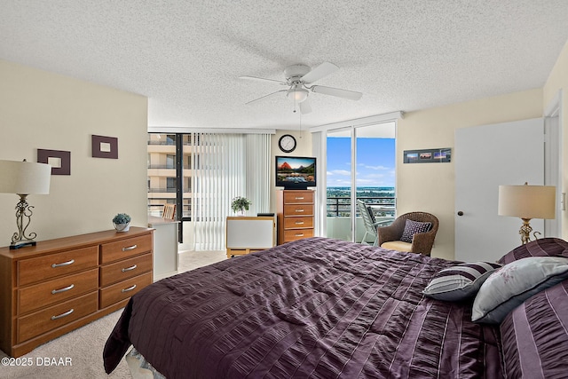 carpeted bedroom featuring expansive windows, ceiling fan, and a textured ceiling