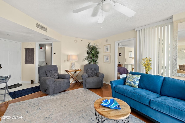 living room with hardwood / wood-style flooring, ceiling fan, and a textured ceiling