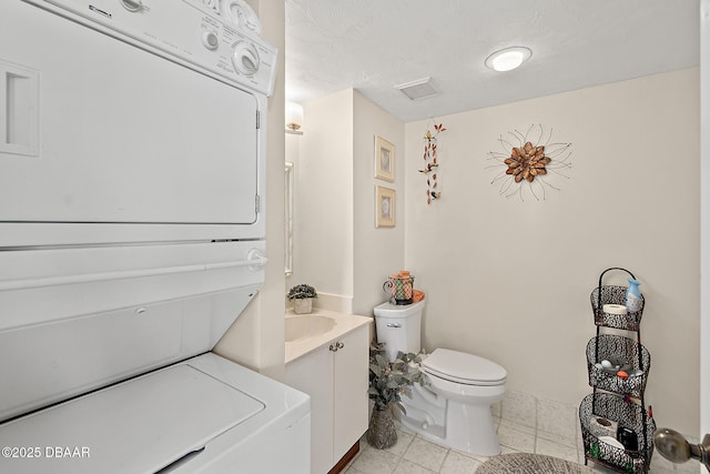 bathroom with stacked washer / dryer, toilet, and vanity