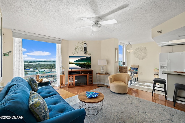 living room featuring floor to ceiling windows, a textured ceiling, and light wood-type flooring