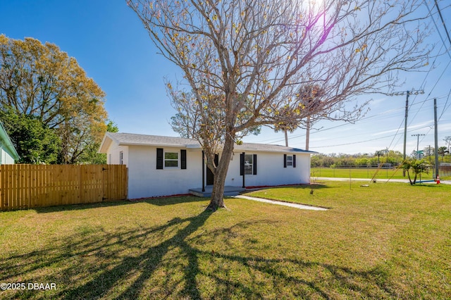 view of front facade with a front lawn, fence, and stucco siding