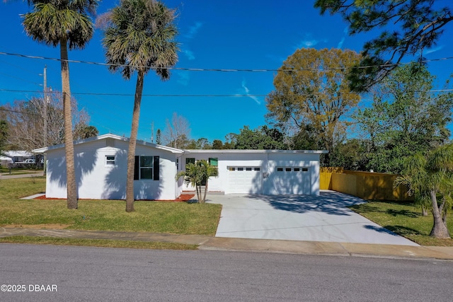 view of front facade featuring a front yard, concrete driveway, an attached garage, and stucco siding