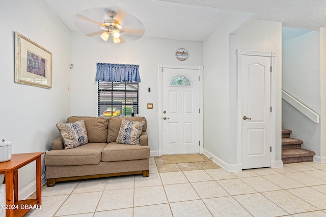 tiled entrance foyer with a textured ceiling and ceiling fan