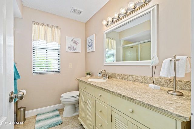 bathroom featuring toilet, vanity, tile patterned floors, and a shower with shower door